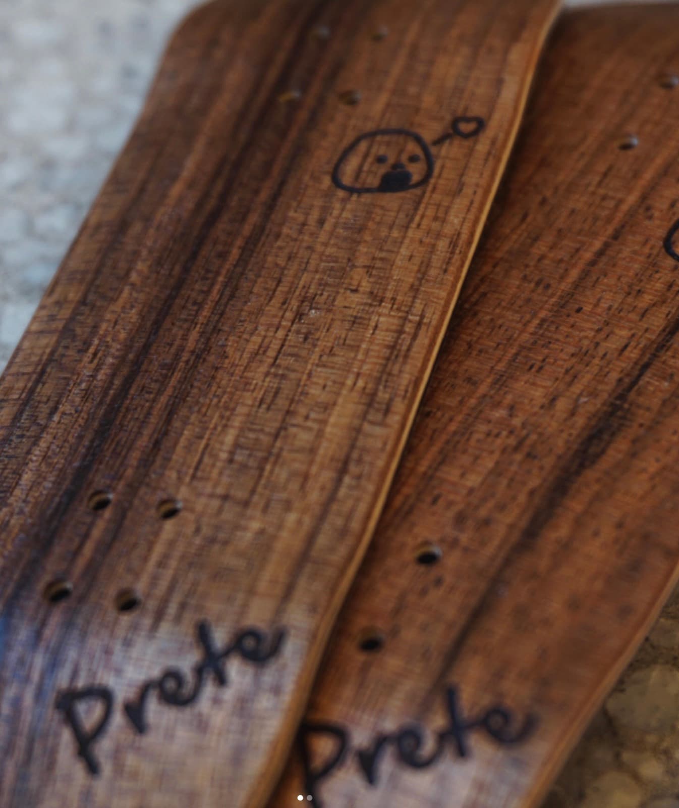 Two natural-wood Prete fingerboard decks with a hand-drawn 'Prete' script and a small rice-ball character burned into the grain.