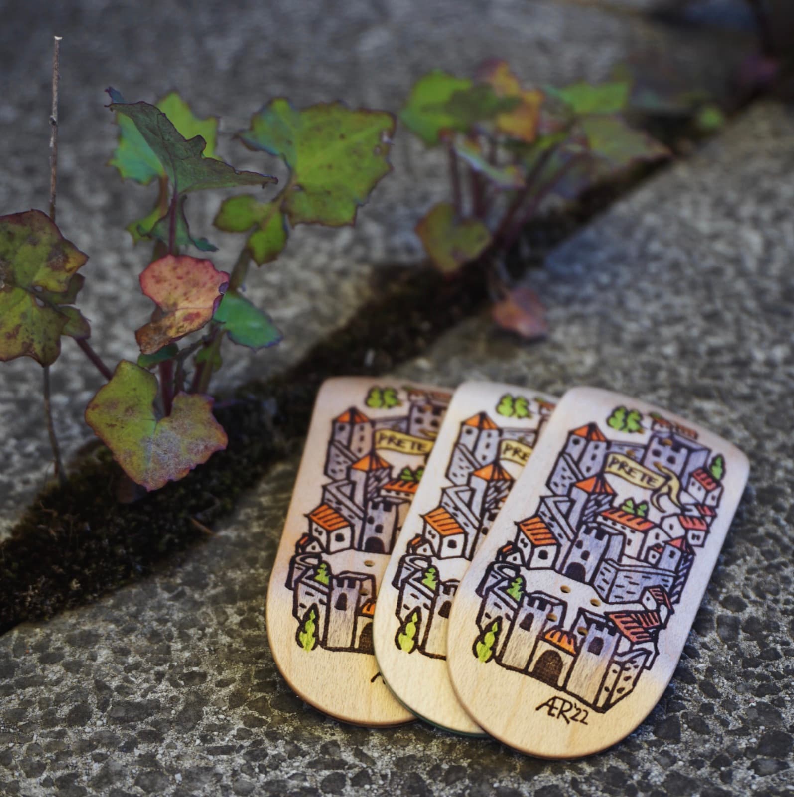Three Prete decks laser-etched and hand-colored with a medieval hilltop-town illustration signed 'ÆR 22'.