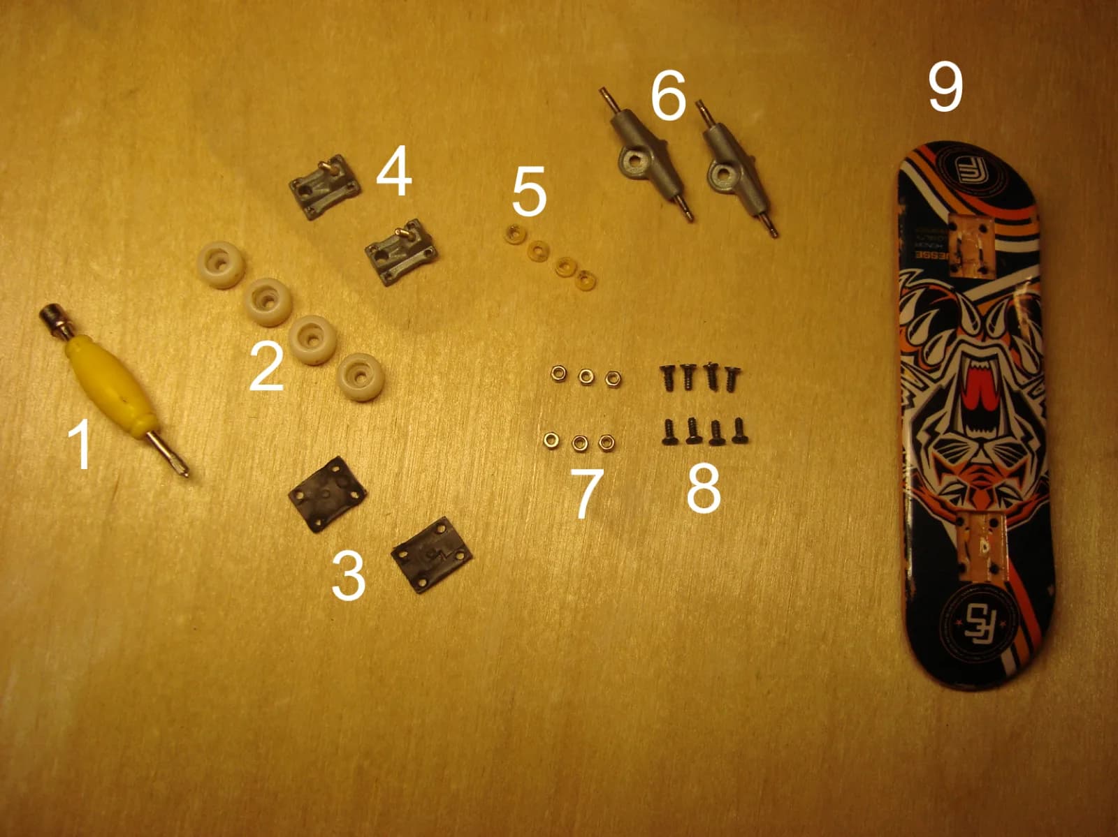 Fingerboard trucks, wheels, and parts arranged as a diagram.