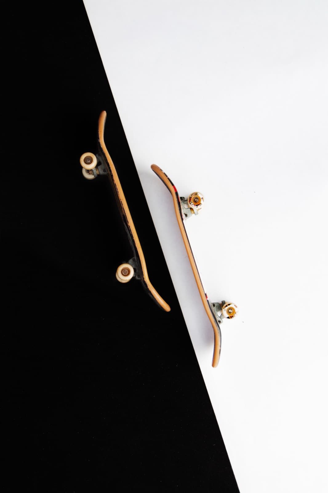Two miniature fingerboard skateboards on a black-and-white surface.
