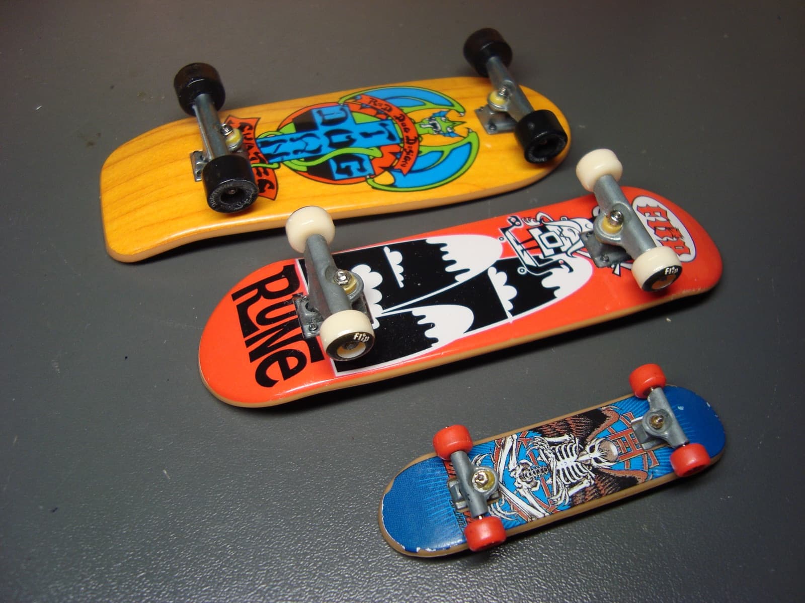A trio of old-school fingerboards with vintage skate graphics and metal trucks.