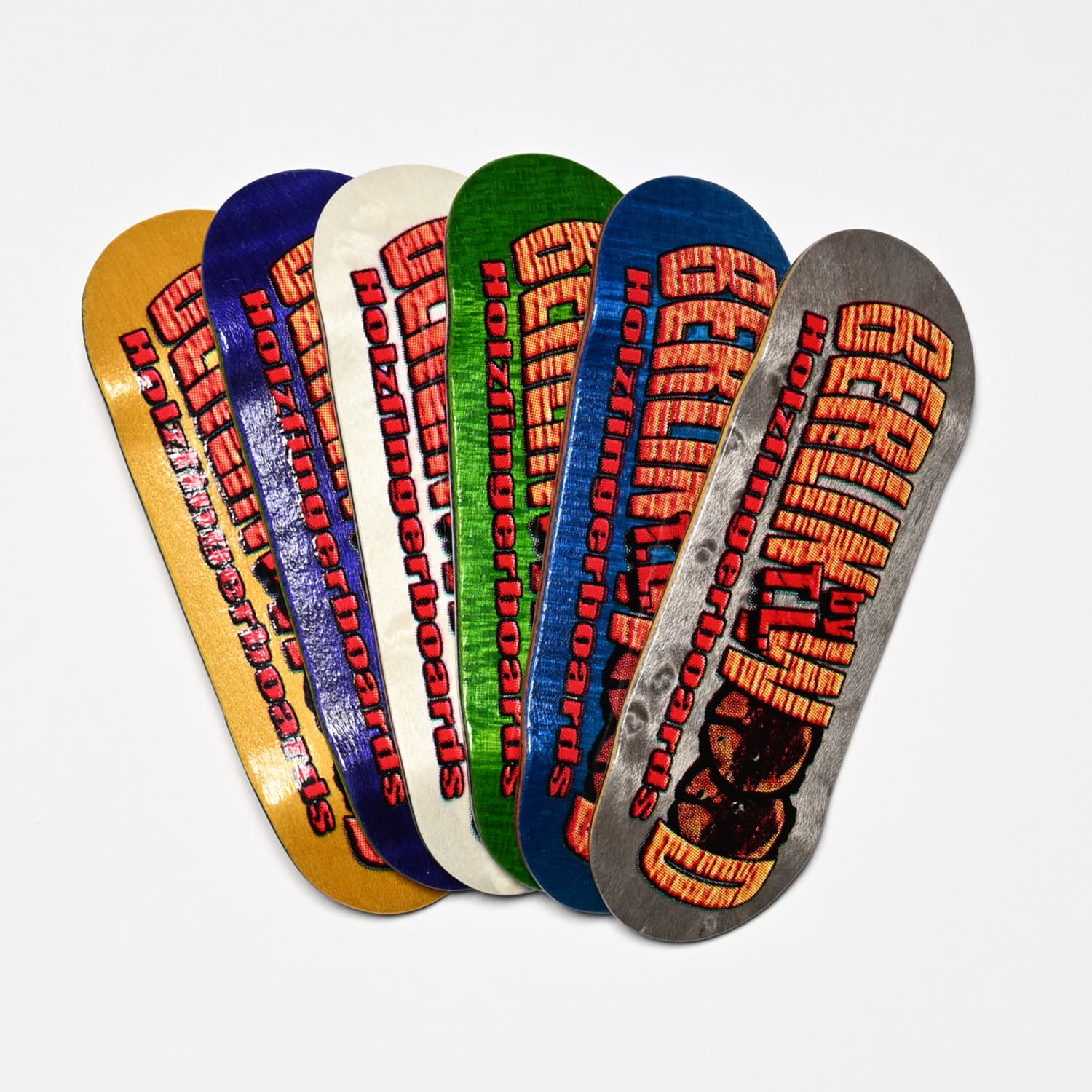 Six Berlinwood fingerboard decks in yellow, purple, white, green, blue and gray are fanned out on a white background.